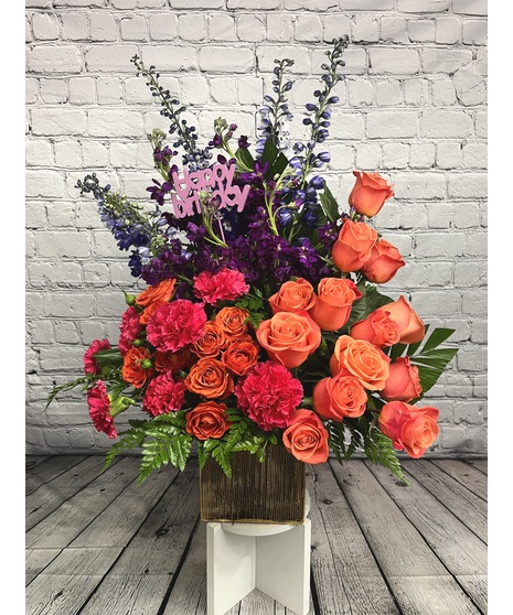 Purple, orange and pink flowers in a cube with Happy Birthday decoration.