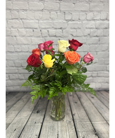 Roses in assorted colors arranged in a clear glass vase.