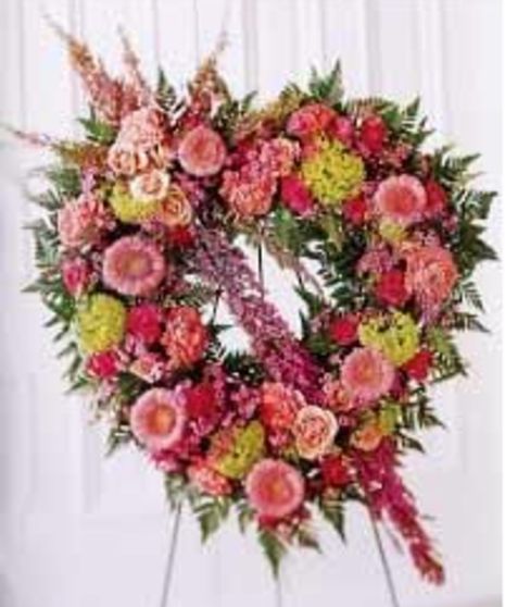 Pastel heart arrangement of assorted flowers presented on an easel. 