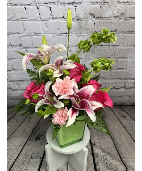 Pink and green flowers in a lime green cube vase.