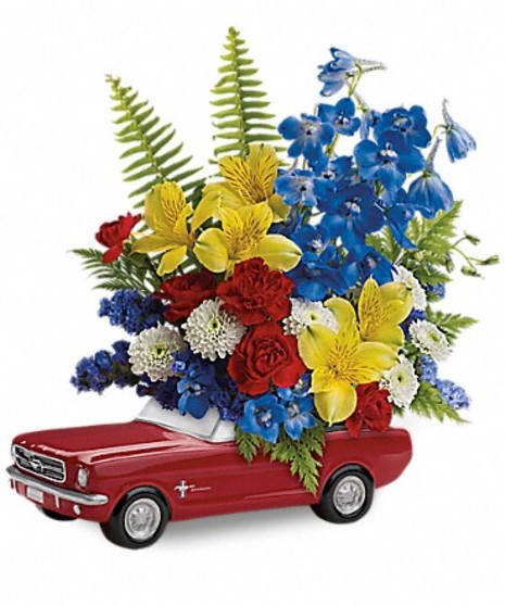 MIniature Ford Mustang container filled with blue, yellow and red flowers and greenery.