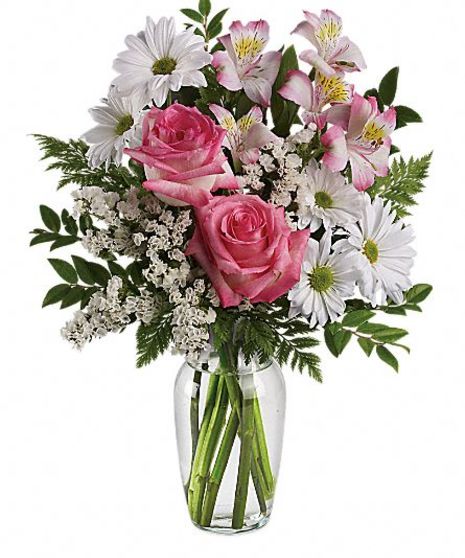 White daisies, pink roses and other assorted flowers in a clear glass vase.