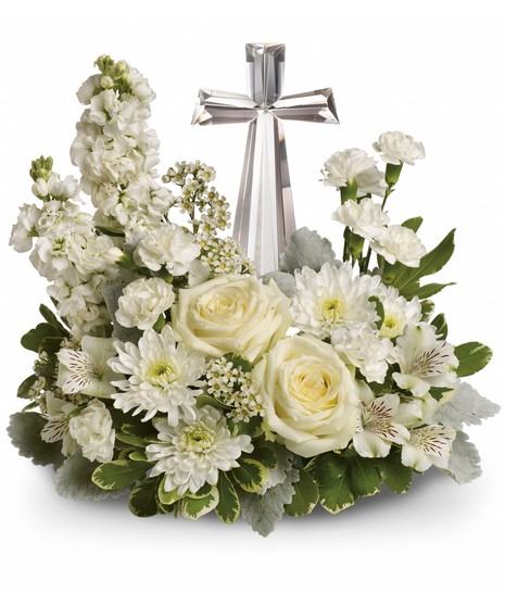 White roses and other flowers surrounding a crystal cross.