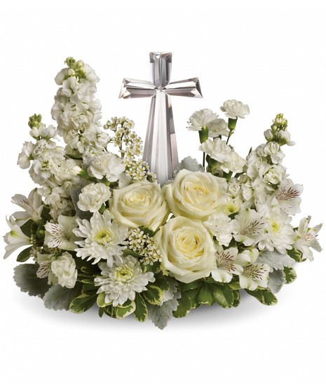 White roses and other flowers surrounding a crystal cross.